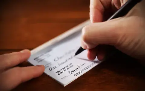 Person writing a donation check to contribute to their donor advised fund.