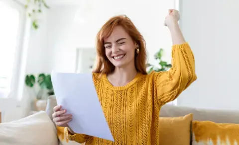Woman in yellow sweater celebrates her budget worksheet