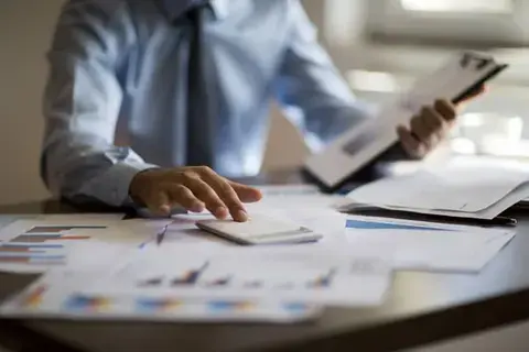 A tax preparer looking intently at tax documents, calculating figures, and double-checking details to ensure a successful filing.