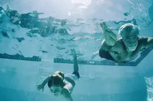Grandfather and grandson swimming underwater